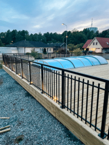 Svart pulverlakkert bassengrekkverk i Alu Retro-design rundt terrasse med tredekke – klassisk og barnesikkert.