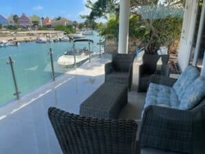 Glassrekkverk med rustfrie stolper på terrasse med utsikt over båtkai og fargerike hus – perfekt glassrekkverk terrasse.