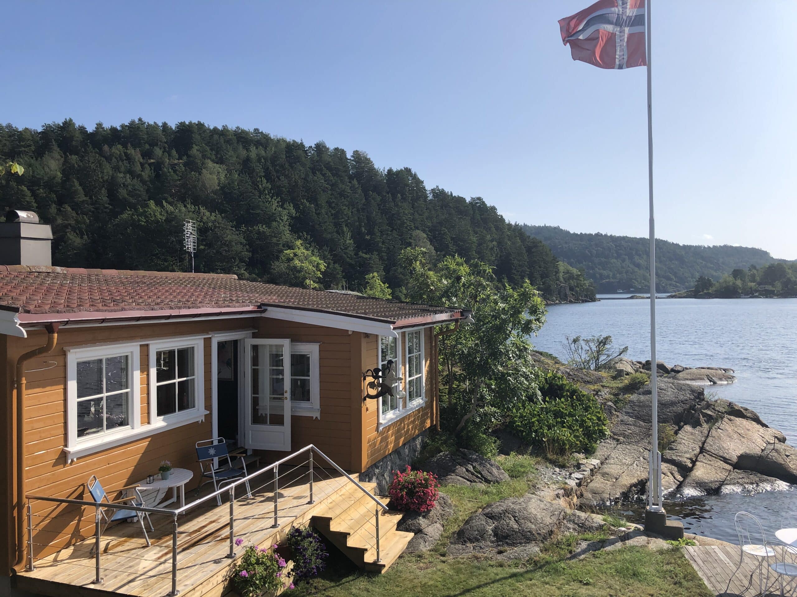 Treterrasse med lavt vajerrekkverk i rustfritt stål ved blomsterbed og krukker – dekorativ og trygg hagekant